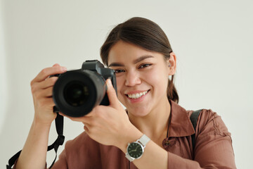 Happy young female photographer with photocamera taking pictures in isolation during photo session...