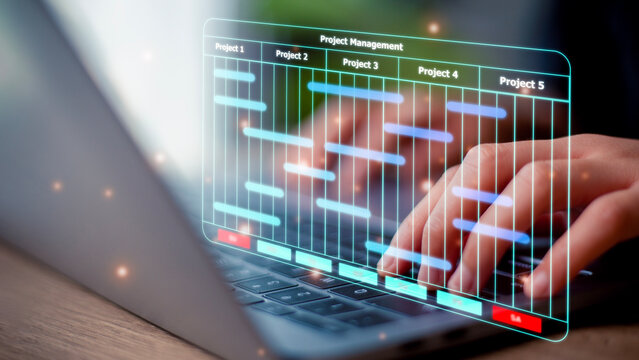 The project manager works on laptop and updates tasks and milestones progress planning with Gantt chart scheduling interface for the company on a virtual screen. Business Project Management System.