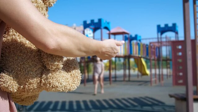 International missing children day. A view of man with plush toy ask for alone child on playground.