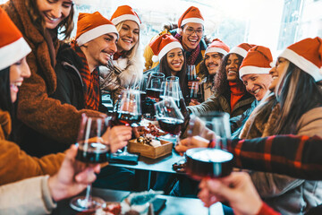 Happy people wearing santa claus hat having Christmas dinner party - Cheerful group of friends celebrating new year together - Winter holidays concept - 660163731