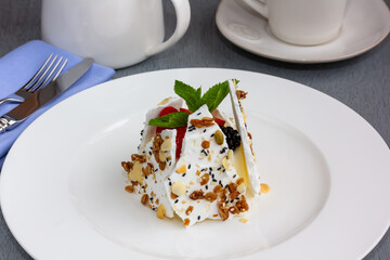 An airy meringue cake with whipped cream is decorated with blueberries, strawberries and mint leaves. Pavlov's dessert. Vertical. Dessert.