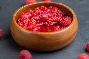 crumpled juicy red raspberries in a wooden bowl