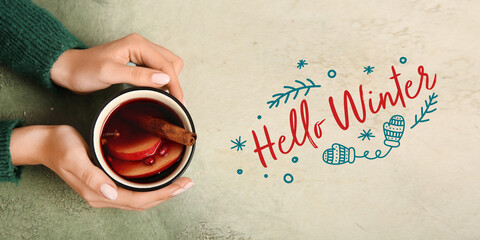 Banner with hands holding mug of delicious mulled wine and text HELLO, WINTER