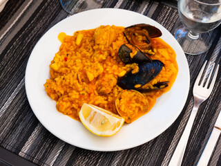 Authentic chicken and seafood paella with creamy lemon sauce .