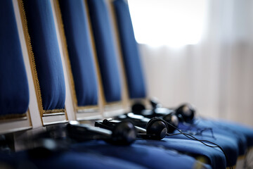 Multiple language translation wireless headphones on blue elegant chairs before conference