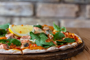 Delicious hot pizza with salmon, red caviar, tomatoes and aragula ready to eat. banner, menu, recipe place for text, top view.