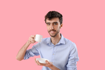 Young businessman with cup of coffee on pink background