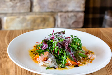 Fresh crispy salad with vegetables and seafood (shrimps) in a white plate on a light background. Healthy food concept.