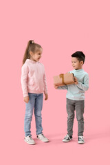 Cute little children in sweaters with gift on pink background