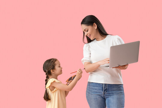 Working mother and her little daughter with paint palette on pink background
