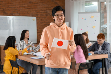 Young Asian man with Japanese flag at language school - obrazy, fototapety, plakaty