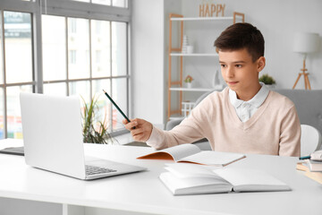 Little boy studying online with laptop at home
