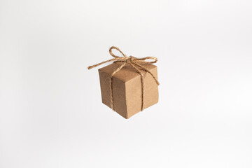 Box package wrapped in brown kraft paper and tied with rough twine, isolated on white background. Floating kraft cube box