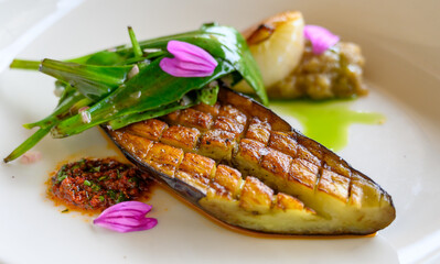 Exquisite vegetarian grilled eggplant dish of modern French haute cuisine prepared with fresh organic ingredients from restaurant own garden and farm and beautifully served