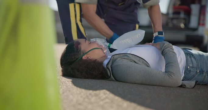 Hands, emergency or oxygen and a paramedic with a woman patient or victim on the street for accident treatment. Healthcare, medical or first aid with an emt working to rescue an injured person