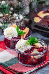 Berry cobbler in glass ramekin with ice cream, Christmas decoration, vertical