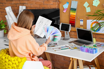 Female fashion designer working with color palettes at table in office
