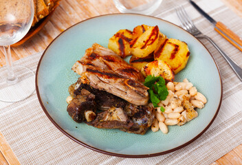 Grilled lamb with beans and roasted potato served with bread.