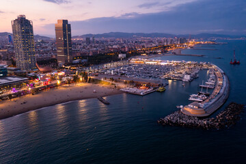 Fototapeta na wymiar Aerial view of seaside area of Barcelona overlooking two modern skyscrapers on Mediterranean coast and marina for pleasure yachts in summer dusk, Spain
