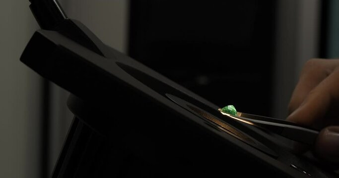 Closeup shot of emerald examined by specialist or gemologist through a microscope. Gem or diamond quality control or inspecting in the laboratory