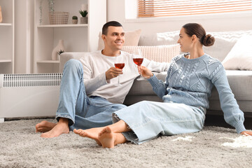 Fototapeta na wymiar Young couple with wine warming near radiator at home