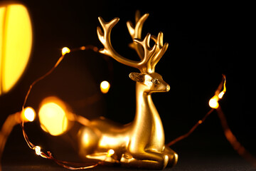 Christmas background. Golden deer and golden bokeh of garlands on a black background.Glowing...