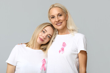 Women with pink ribbons on grey background. Breast cancer awareness concept