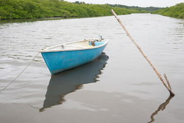 A blue and white boat anchored in a river waiting to depart. Fishing boats.