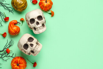 Human skulls with marigold flowers, pumpkins and tree branches on green background