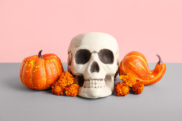 Human skull with marigold flowers and pumpkins on color background