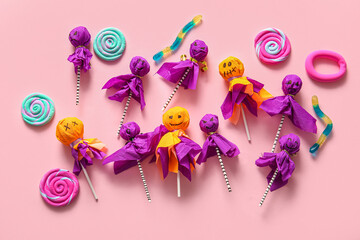Sweet lollipops with jelly worms and candies for Halloween party on pink background