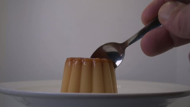 egg and vanilla custard and liquid caramel eaten with a spoon in slow motion on a white background