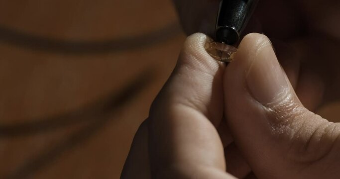 Jeweler or gemologist checking quality inspecting gemstone with gem tester. Close-up shot
