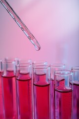 Dripping reagent into test tube with red liquid, closeup. Laboratory analysis