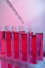 Dripping reagent into test tube with red liquid, closeup. Laboratory analysis