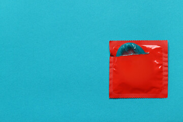 Condom in torn package on light blue background, top view with space for text. Safe sex