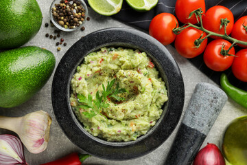 Delicious guacamole and ingredients on grey table, flat lay