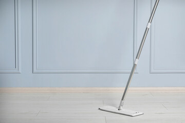 Cleaning of parquet floor with mop indoors, space for text