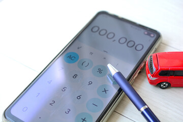 スマートフォンとミニカーで表現する車の維持費のイメージ画像