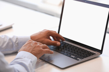 Man using modern laptop at white desk, closeup