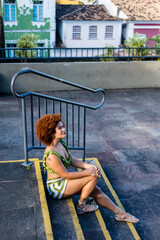 Naklejka premium A beautiful woman with red hair sitting on a staircase next to a stainless steel handrail.