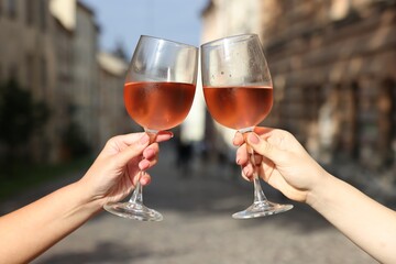 Women clinking glasses with rose wine outdoors, closeup