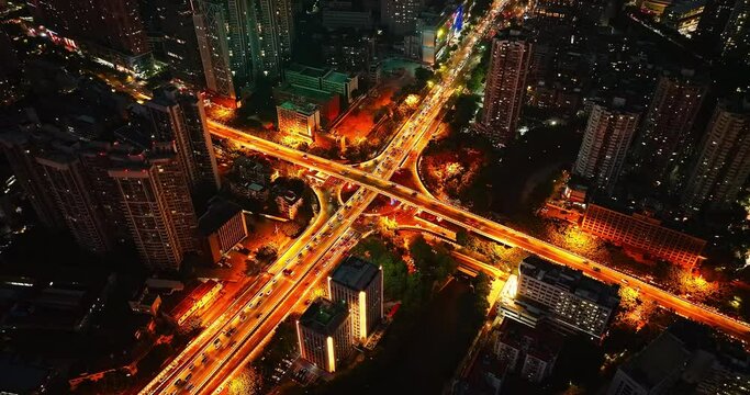 Aerial view of busy city intersection at night. Drone descends to photograph city road.