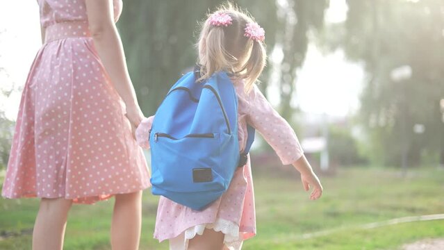 mother and daughter schoolgirl go to school. education learning school concept. mother and daughter with a backpack go to school in the park in lifestyle the summer. girl rushes to school