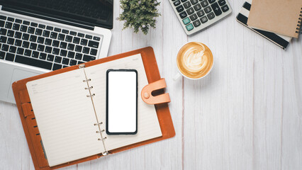 White wooden desk workplace with blank screen smartphone, notebook, laptop, calculator and cup of coffee, Top view flat lay with copy space.