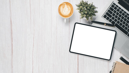 White wooden desk workplace with blank screen tablet, laptop, pen, notebook and cup of coffee, Top...