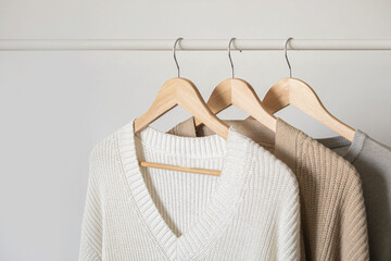 Hanger with neutral beige and white clothes on a white background.