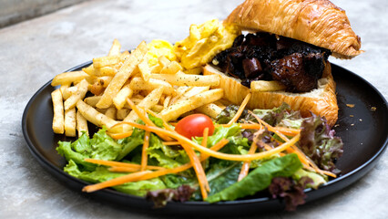 Delicious Grilled Beef Croissant Sandwich with French Fries, Scrambled Egg, and Vegetables - A Perfect Brunch Meal