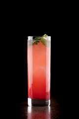 long drink glass of cocktail with red fruits vodka gin mint refreshing front on wooden table