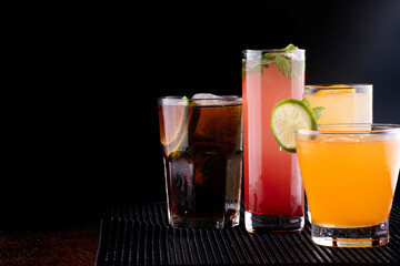 various colorful cocktails prepared on black background with lemonade gin tonic strawberry orange vat vodka juice soda